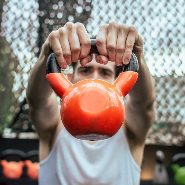 Focused man holding a kettlebell, showing concentration and body control.
